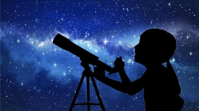 Child and telescope silhouette against a star background